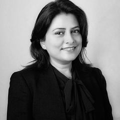 Smiling woman in a dark blazer and blouse, looking towards the camera. Black and white photo.