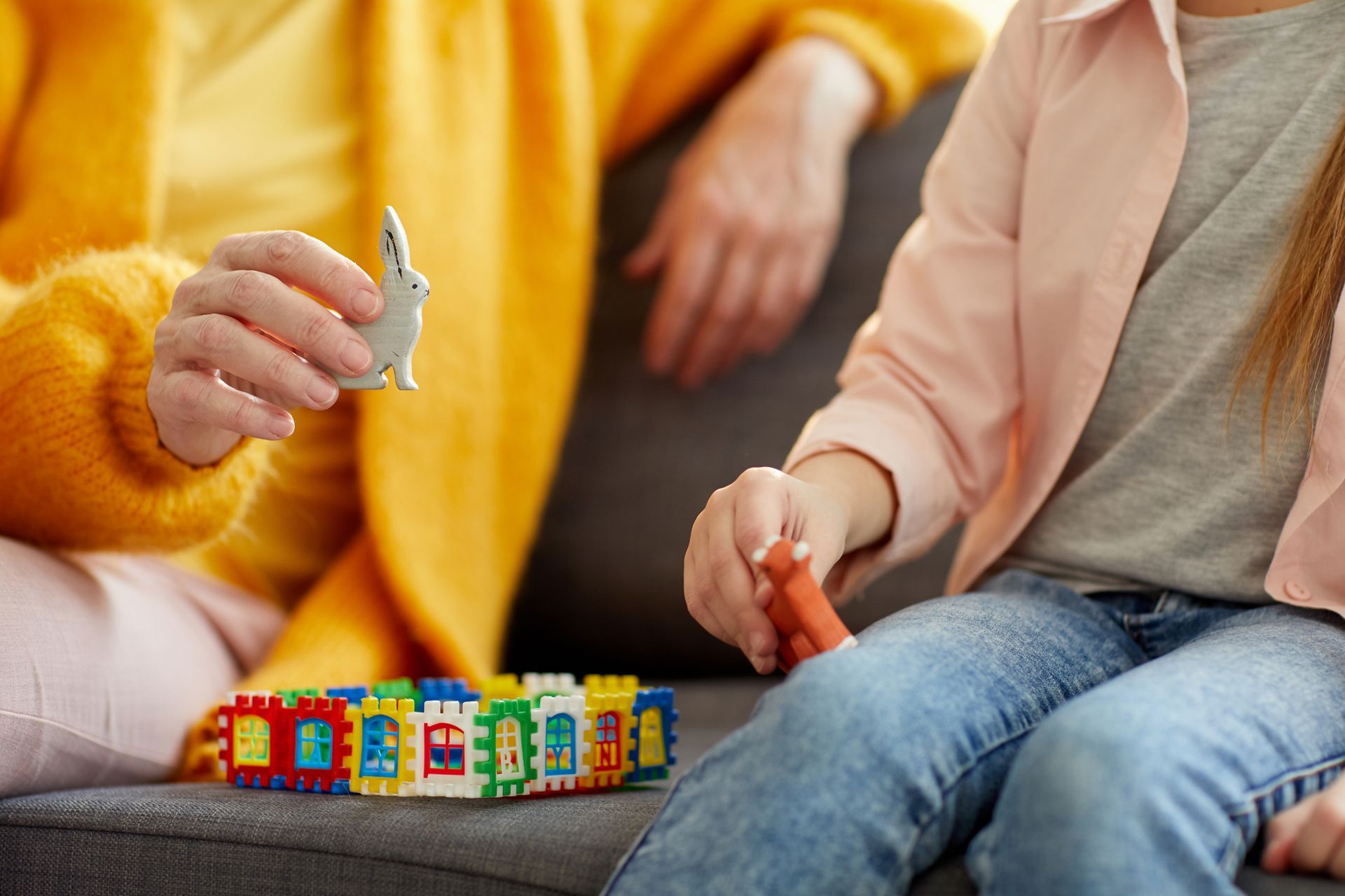 Una mujer y un niño están sentados en un sofá jugando con bloques de lego.