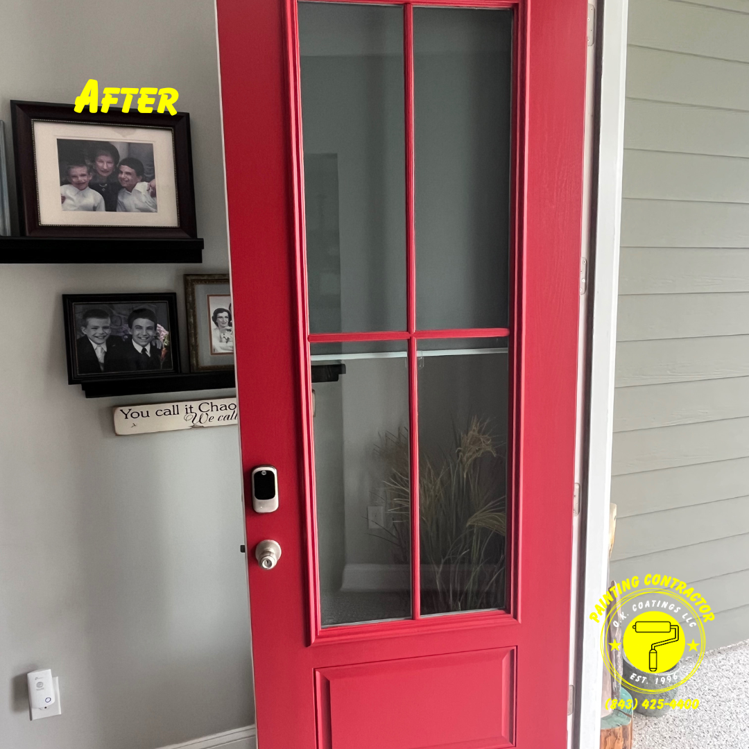 A bright red front door with a glass window insert, featuring a modern smart lock and handle, next to a wall with photos.