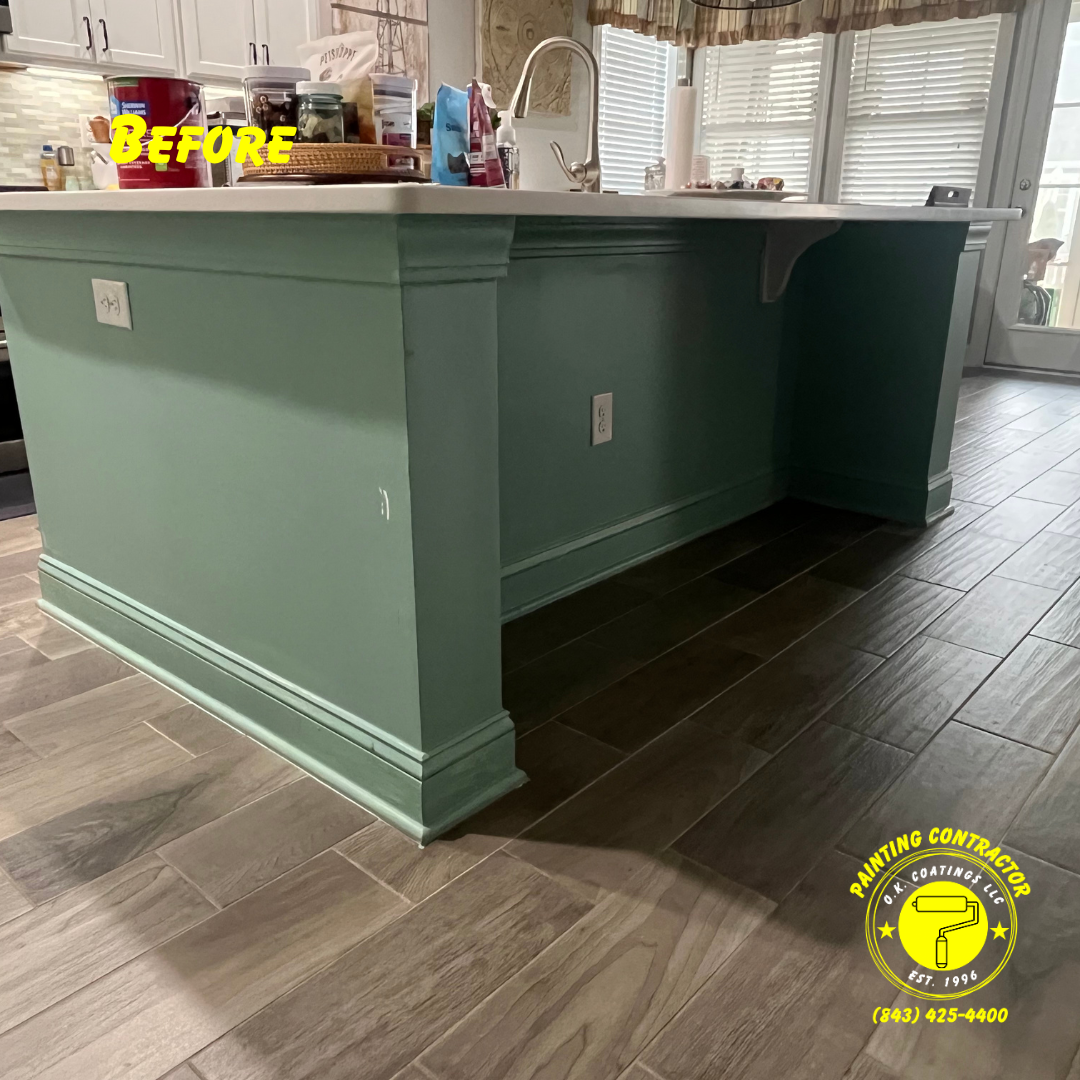 A sage green kitchen island base with decorative molding and trim, shown before renovation, on a wood-look tile floor.