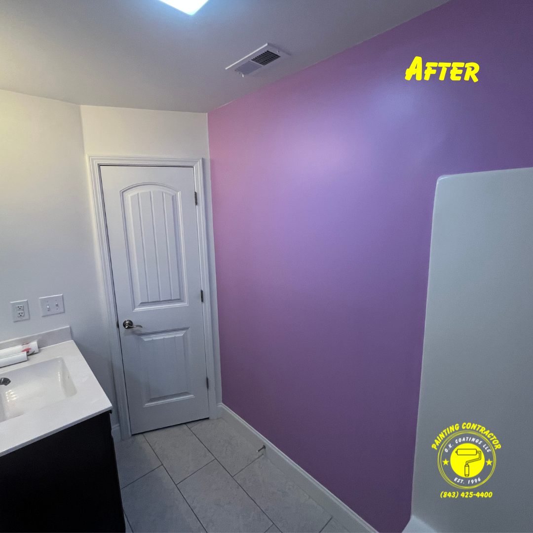 A bathroom interior showing a newly painted lavender wall next to a white door, vanity, and shower surround.
