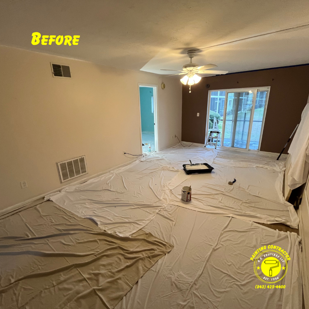 A room prepared for painting, with drop cloths covering the floor, a paint tray, and a dark brown accent wall.