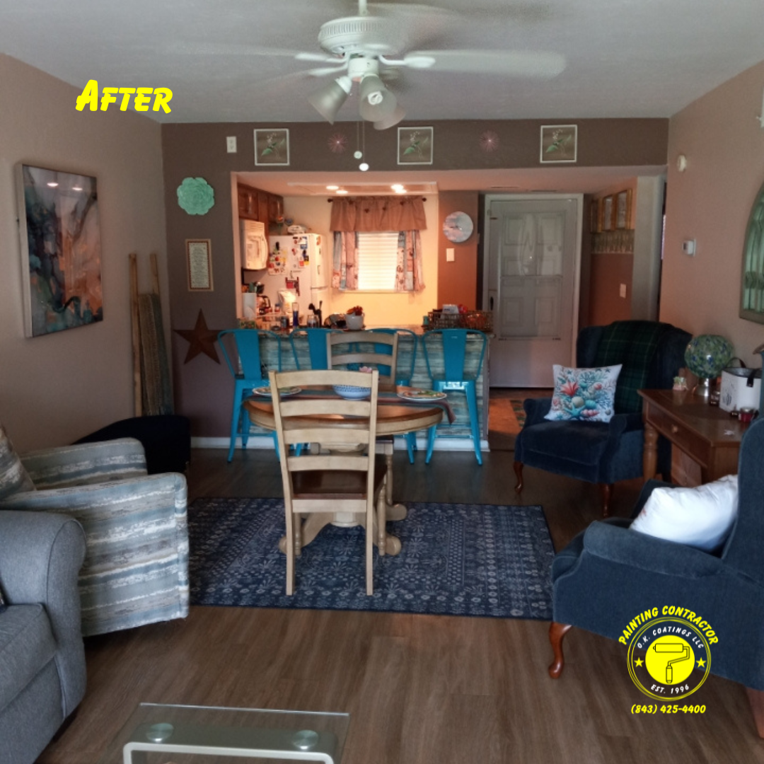 A renovated living and dining room with neutral walls, wood flooring, a blue rug, and turquoise bar stools at a counter.