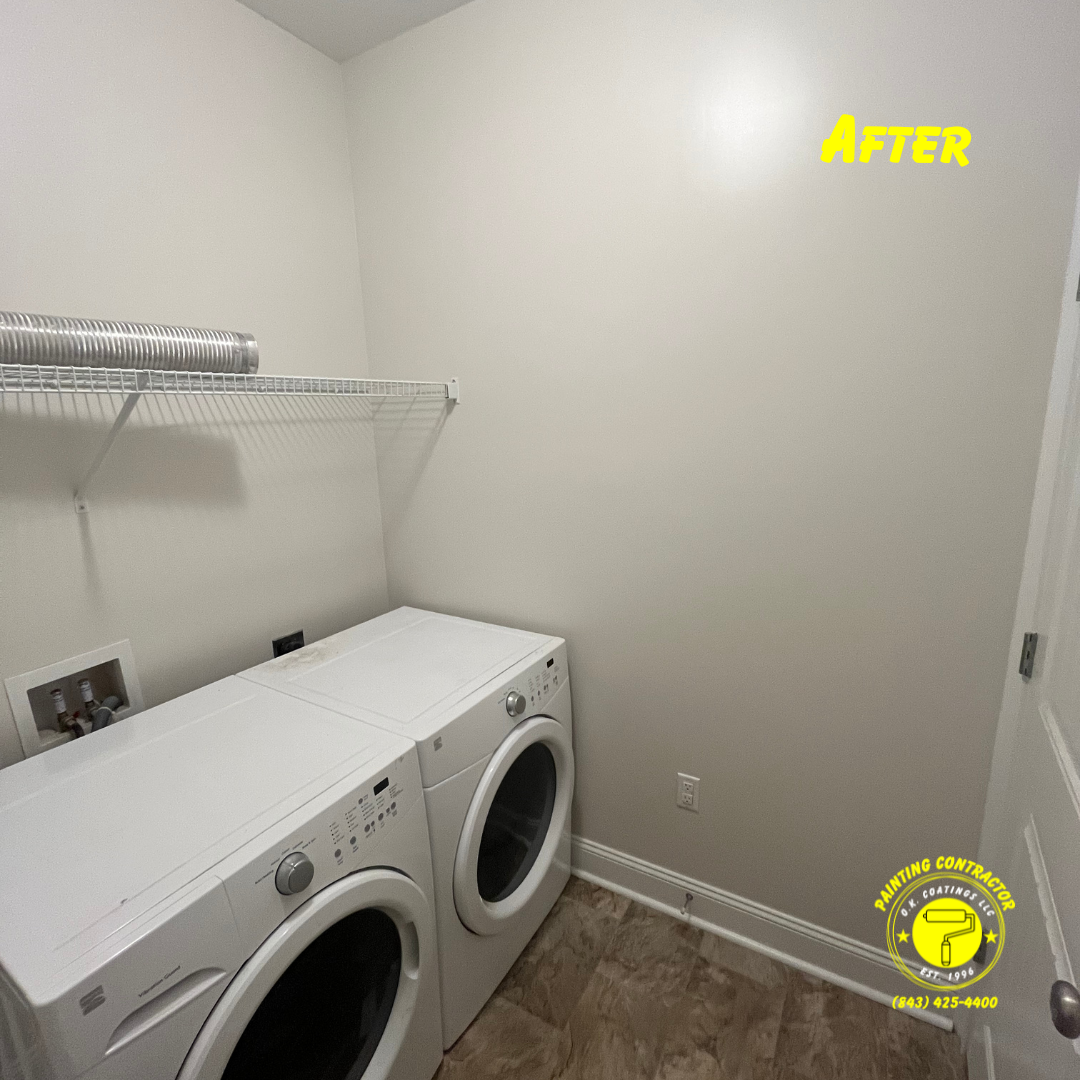 A laundry room with two white washing machines, a wire shelf, and light beige walls after a painting project.