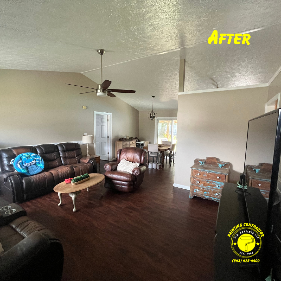 A living room with tan walls, brown leather furniture, dark wood floors, and a vaulted ceiling with a ceiling fan.