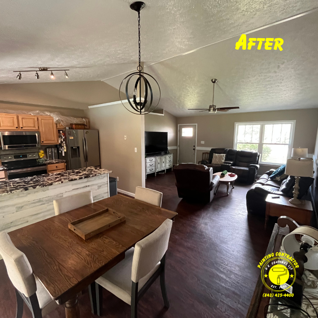 A renovated open-concept home interior featuring a dining area, kitchen, and living room with brown flooring and beige walls.