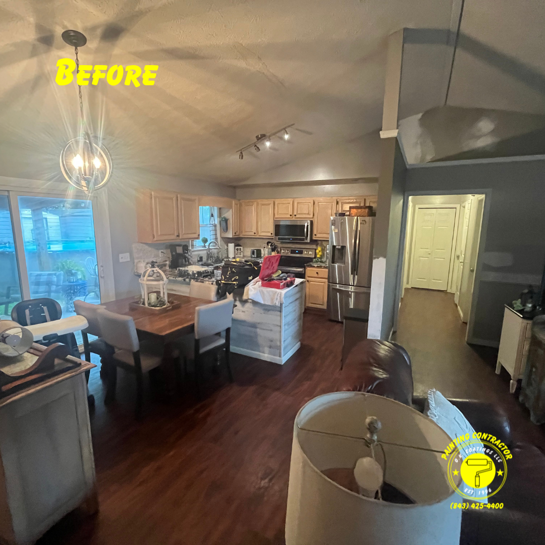 A before photo showing a home interior with a wooden dining table, light wood kitchen cabinets, and brown flooring.