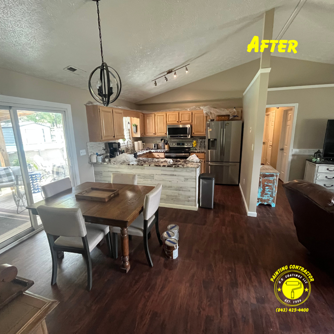 An interior shot of a dining area and kitchen with dark wood floors, light wood cabinets, and a white shiplap island.