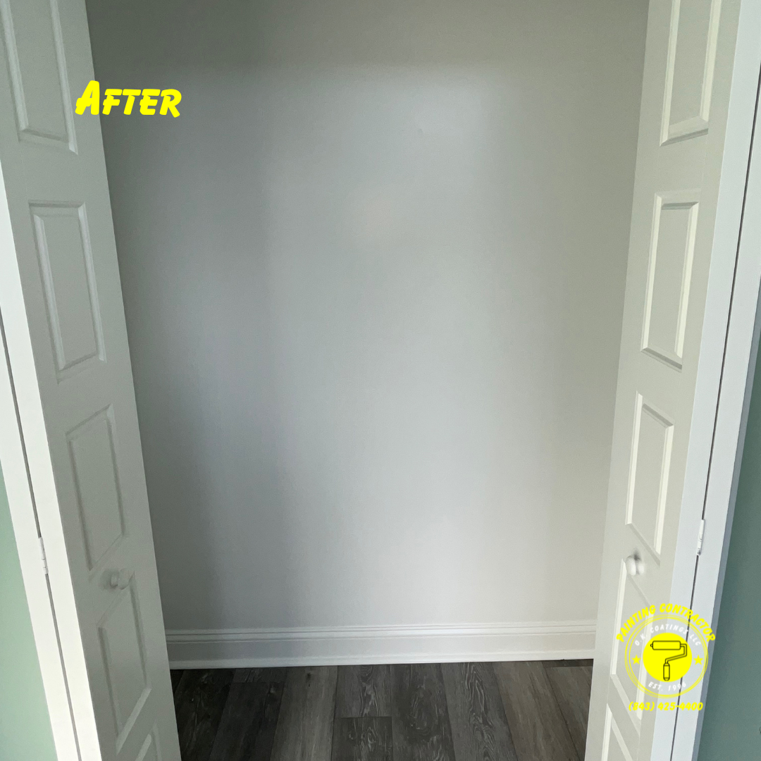 A clean, freshly painted interior closet space with white walls, baseboards, and grey wood flooring.