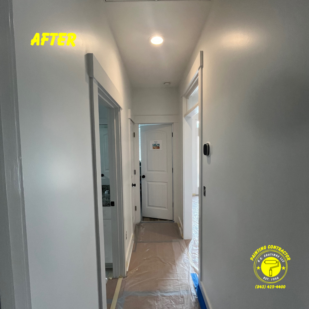 A bright hallway painted light gray with white trim and doors, featuring protective plastic on the floor.