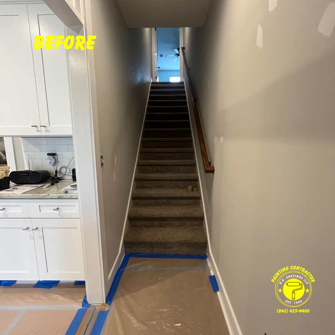 A staircase with carpeted steps between light gray walls, with a kitchen area on the left and protective floor covering.