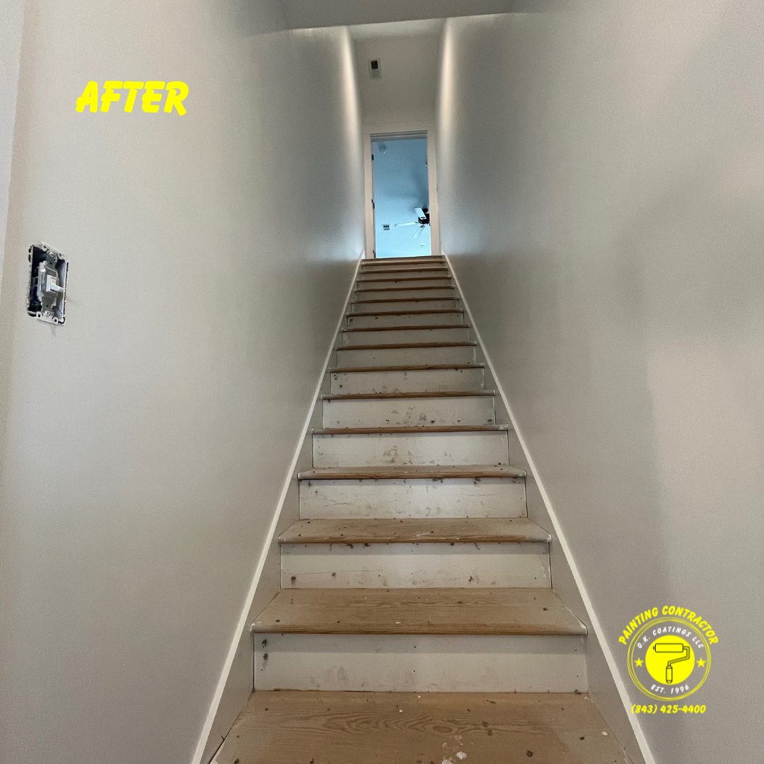 A narrow, straight staircase with light gray walls, wooden treads, and white risers leading to a doorway at the top.