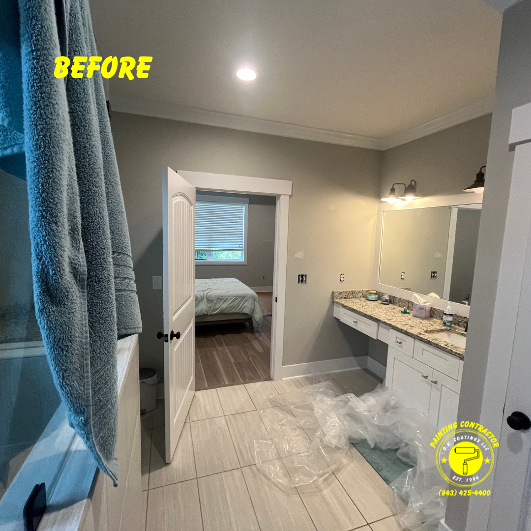 A bathroom undergoing renovation with beige tile floors, a white vanity, a large mirror, and an open door to a bedroom.