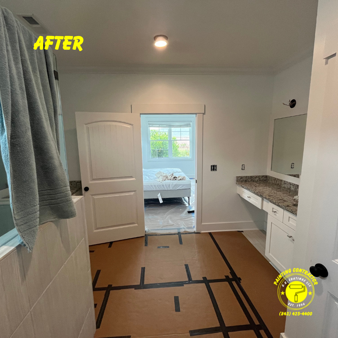 A renovated bathroom with white walls, a granite-topped vanity, and protective floor covering, leading into a bedroom.