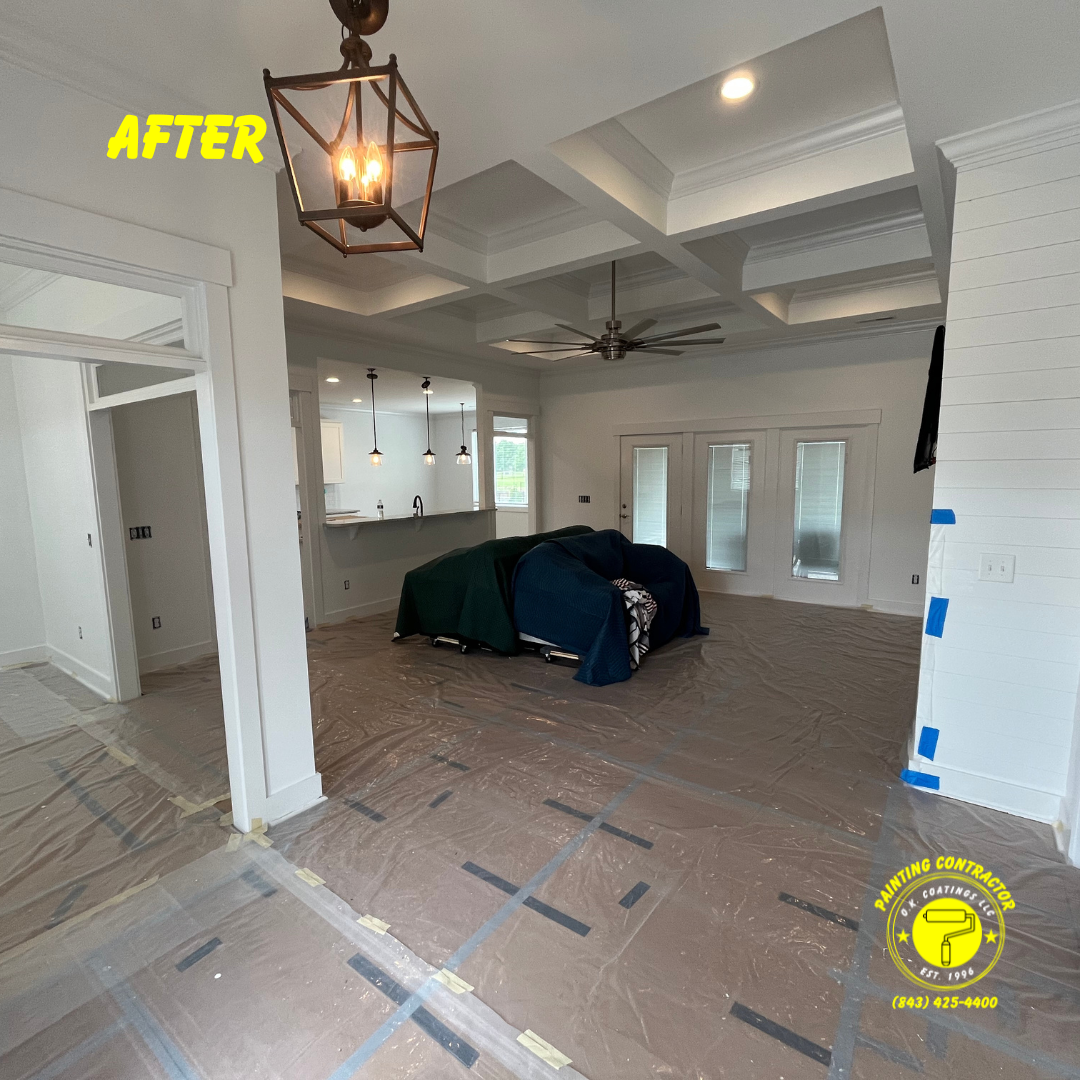 A bright, newly painted white room with a coffered ceiling, pendant lighting, and protective film covering the floor.