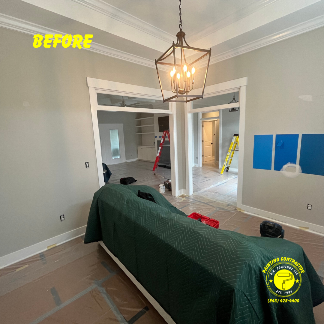 A room under renovation with light gray walls, a lantern chandelier, protective furniture covers, and blue paint samples.