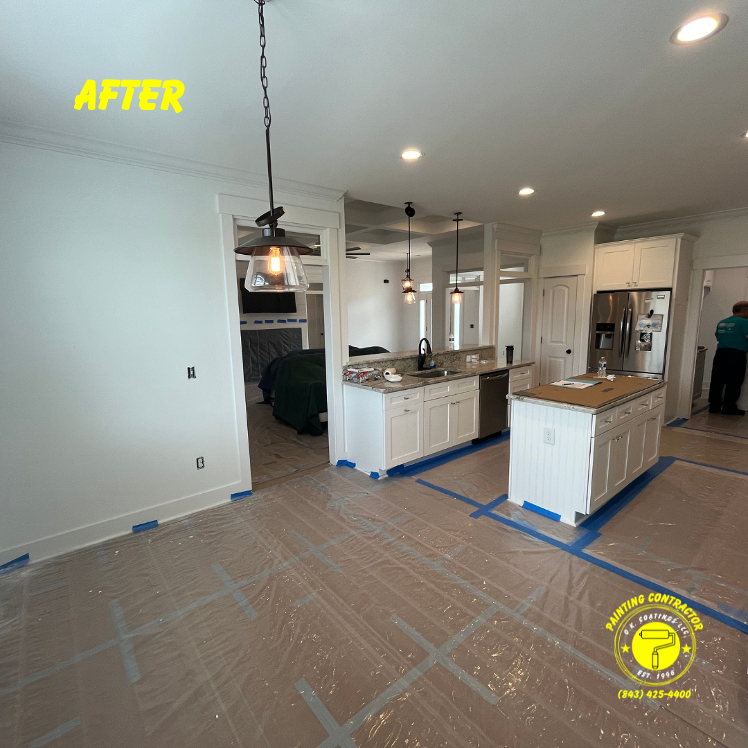 A white kitchen with a center island and hardwood floors covered in protective plastic sheeting during renovations.