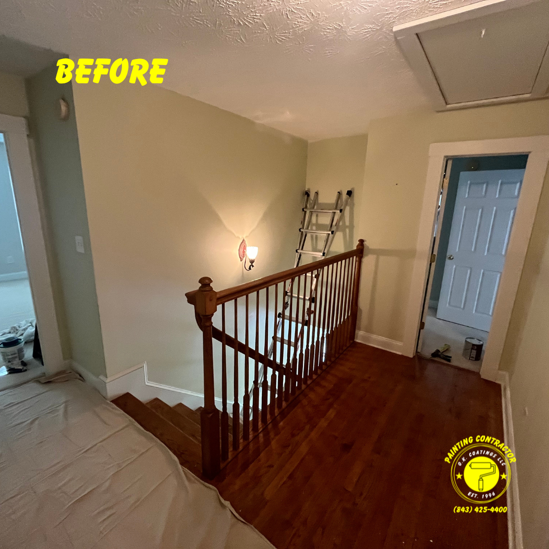 A staircase and hallway under renovation with a ladder leaning against a wall and drop cloths on the floor.