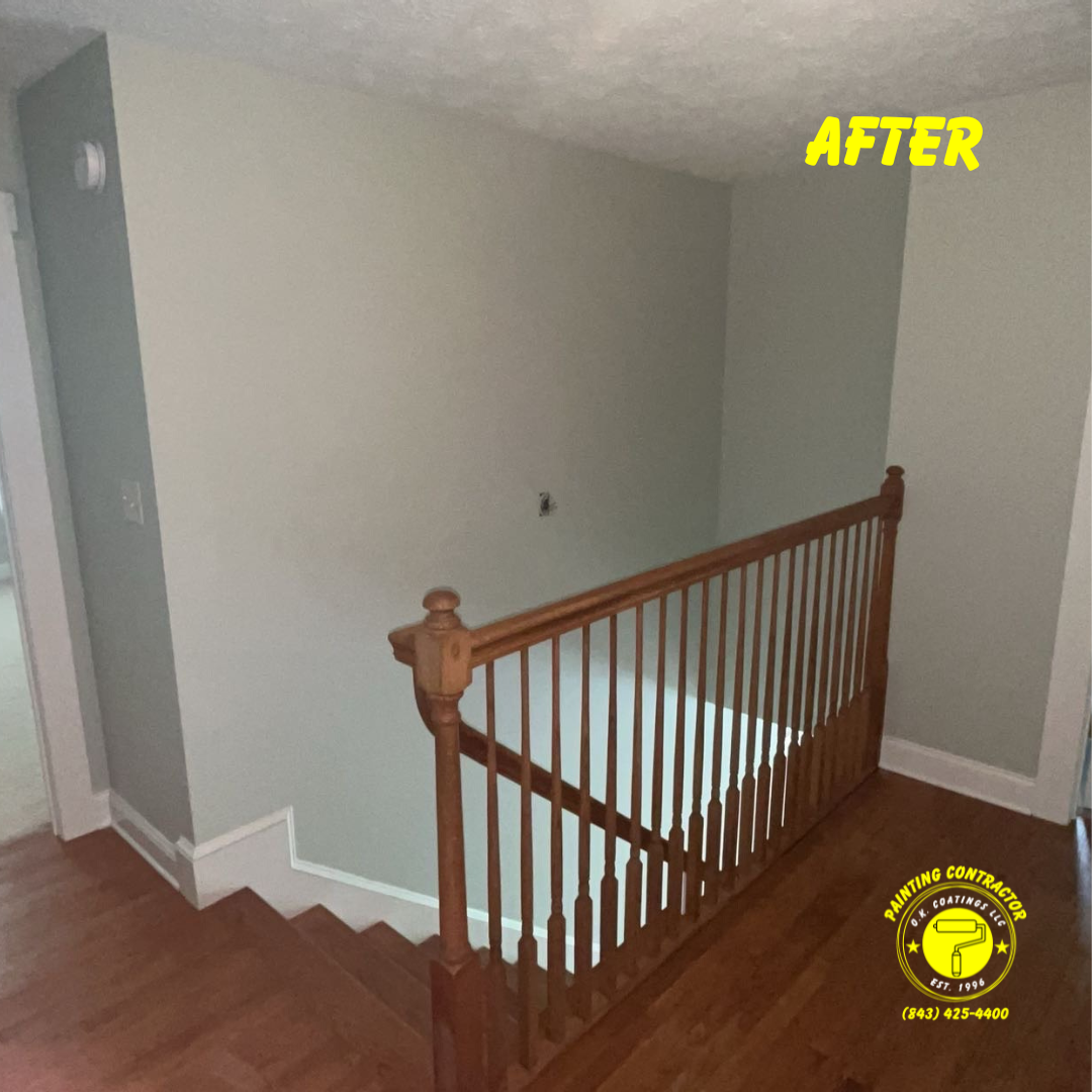 A stairwell with light green walls, a wooden railing, and hardwood floors after a professional painting project.