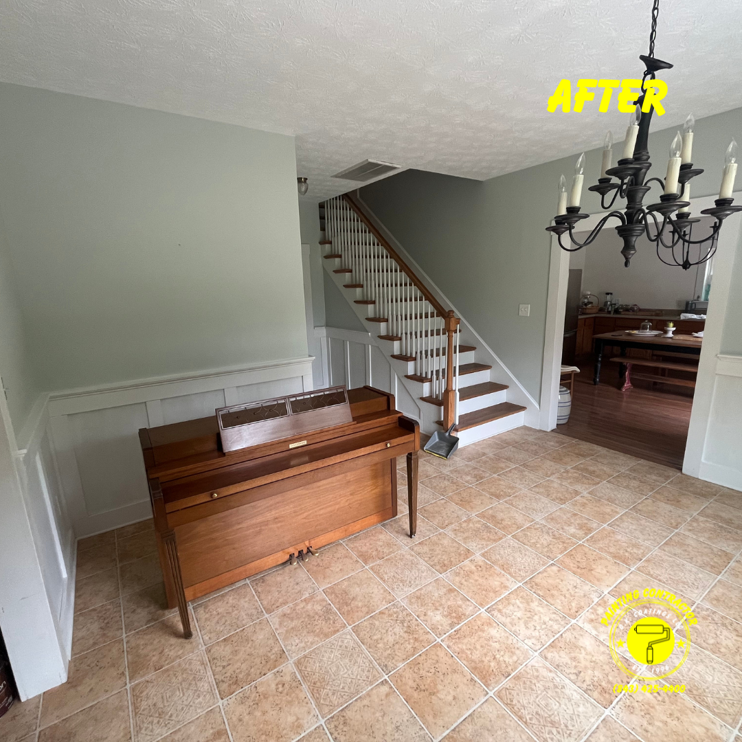 An entryway with a piano, a staircase with white spindles, gray walls, and tile flooring, labeled as an 