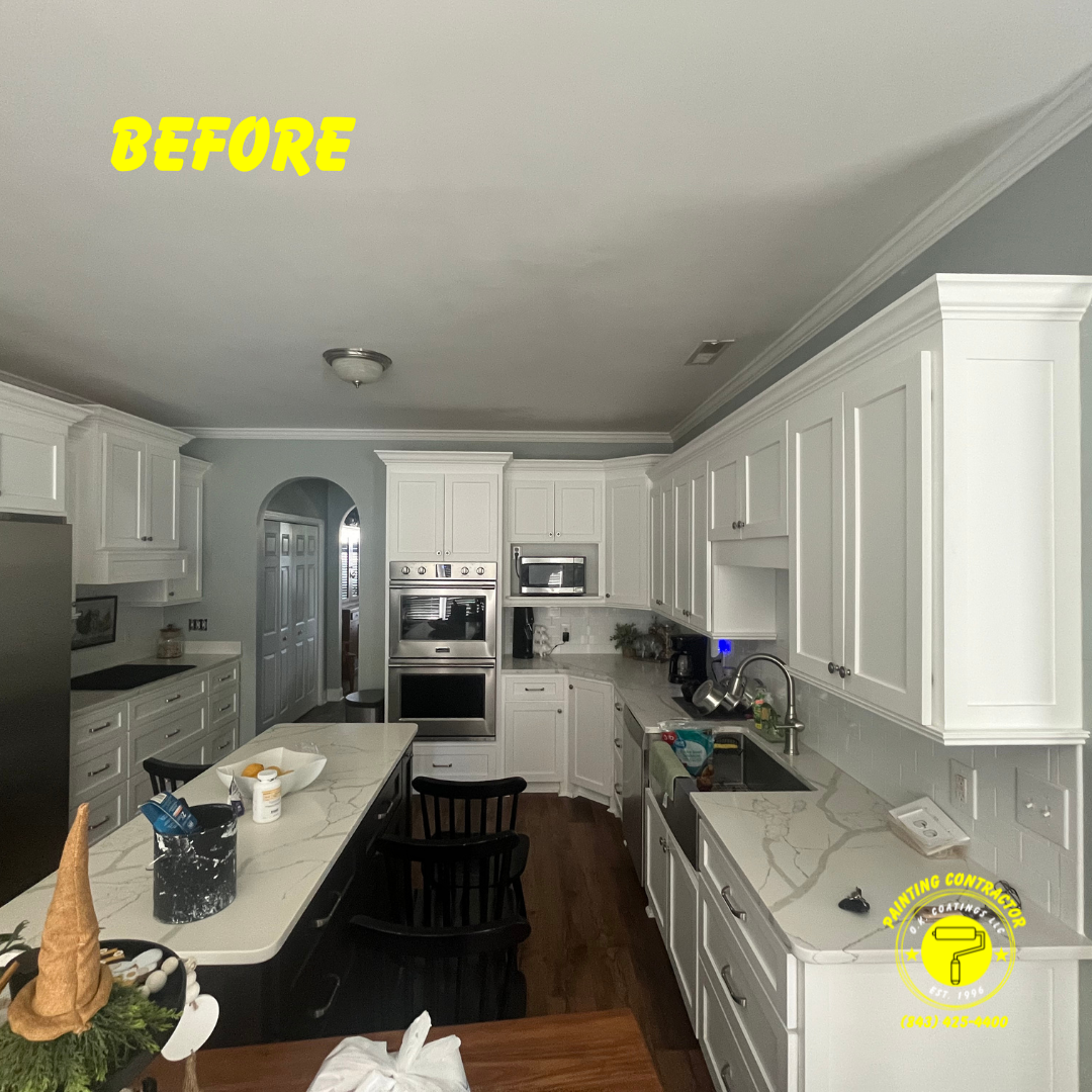 A brightly lit kitchen with white cabinets, a central island with marble-look countertops, and dark flooring.