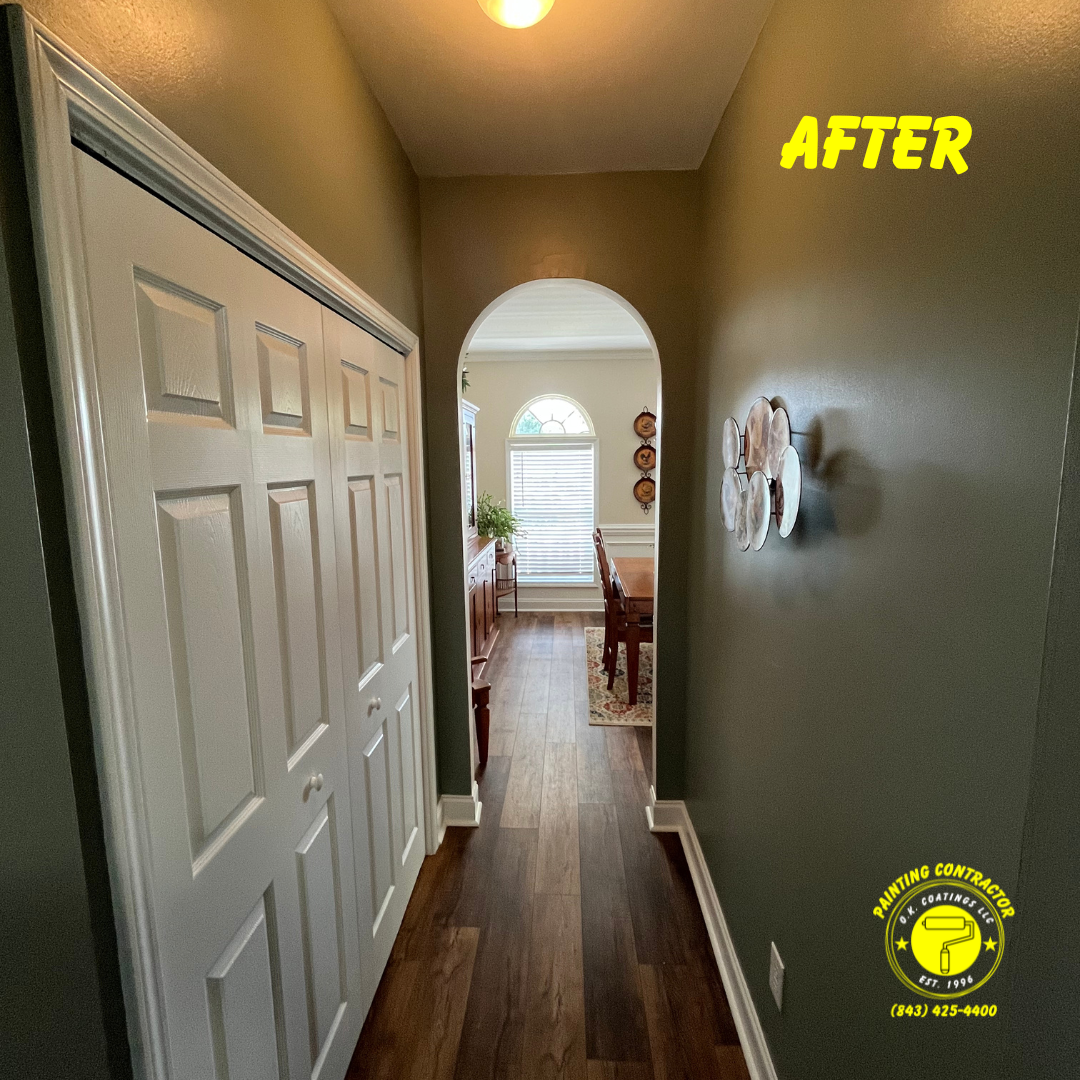 A hallway with dark olive-green walls, white paneled closet doors on the left, and an arched doorway leading to a room.