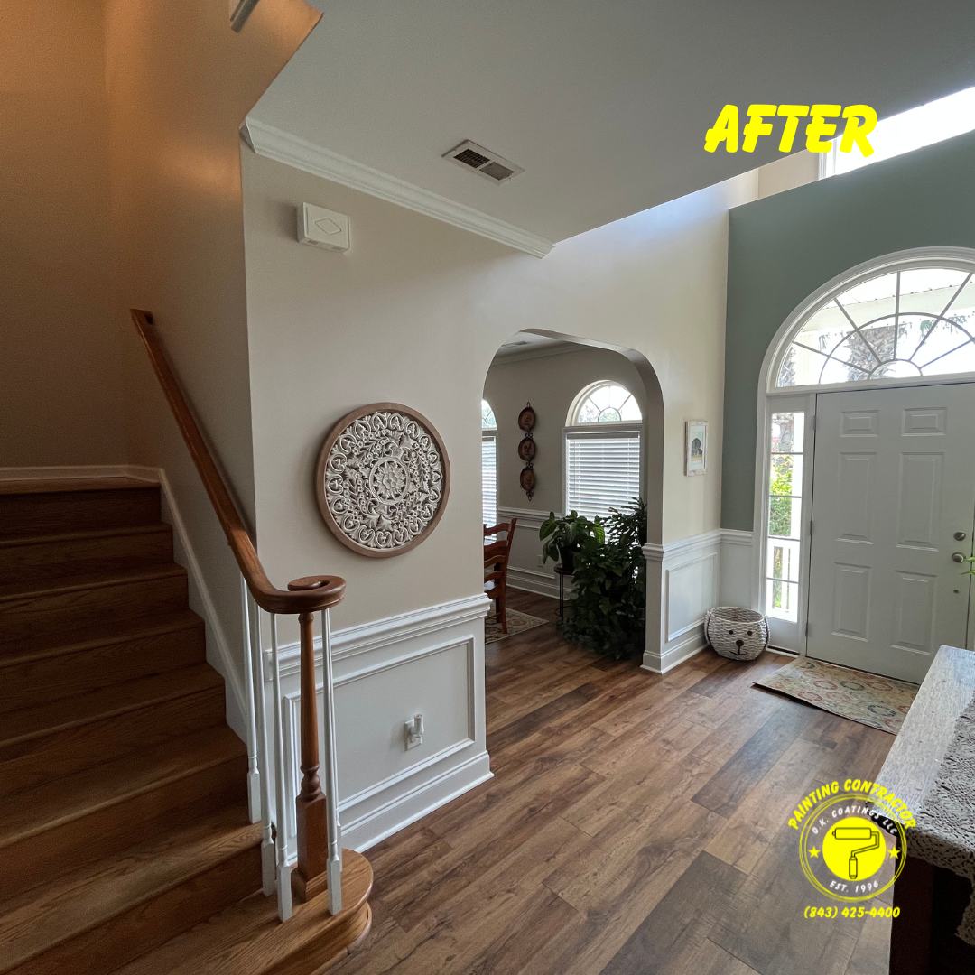 A bright entryway features wood stairs, white wainscoting, light beige walls, and dark hardwood floors under an arched door.
