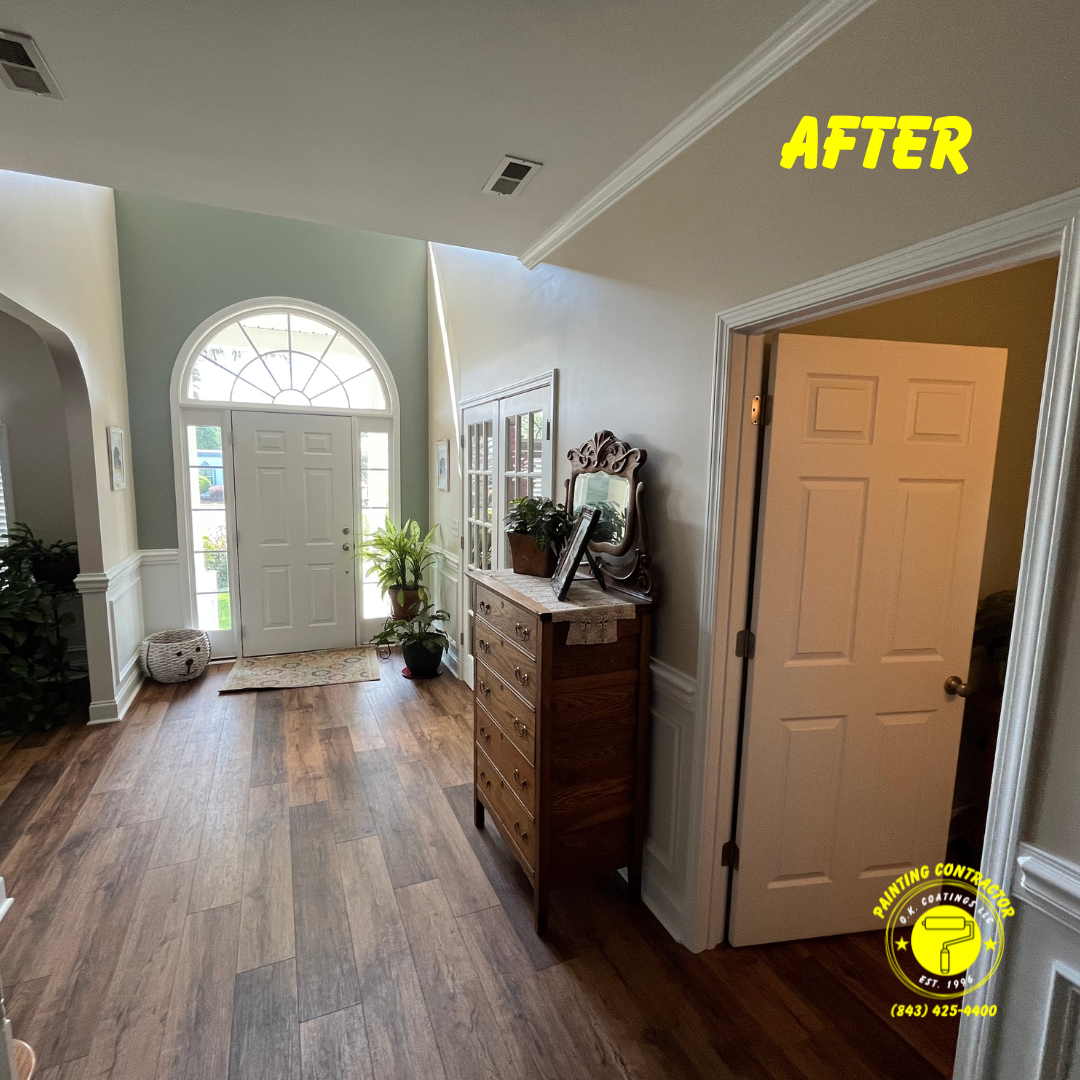 A bright, neutral-toned entryway with wood-look flooring, white doors, a dresser, and a green accent wall by the door.