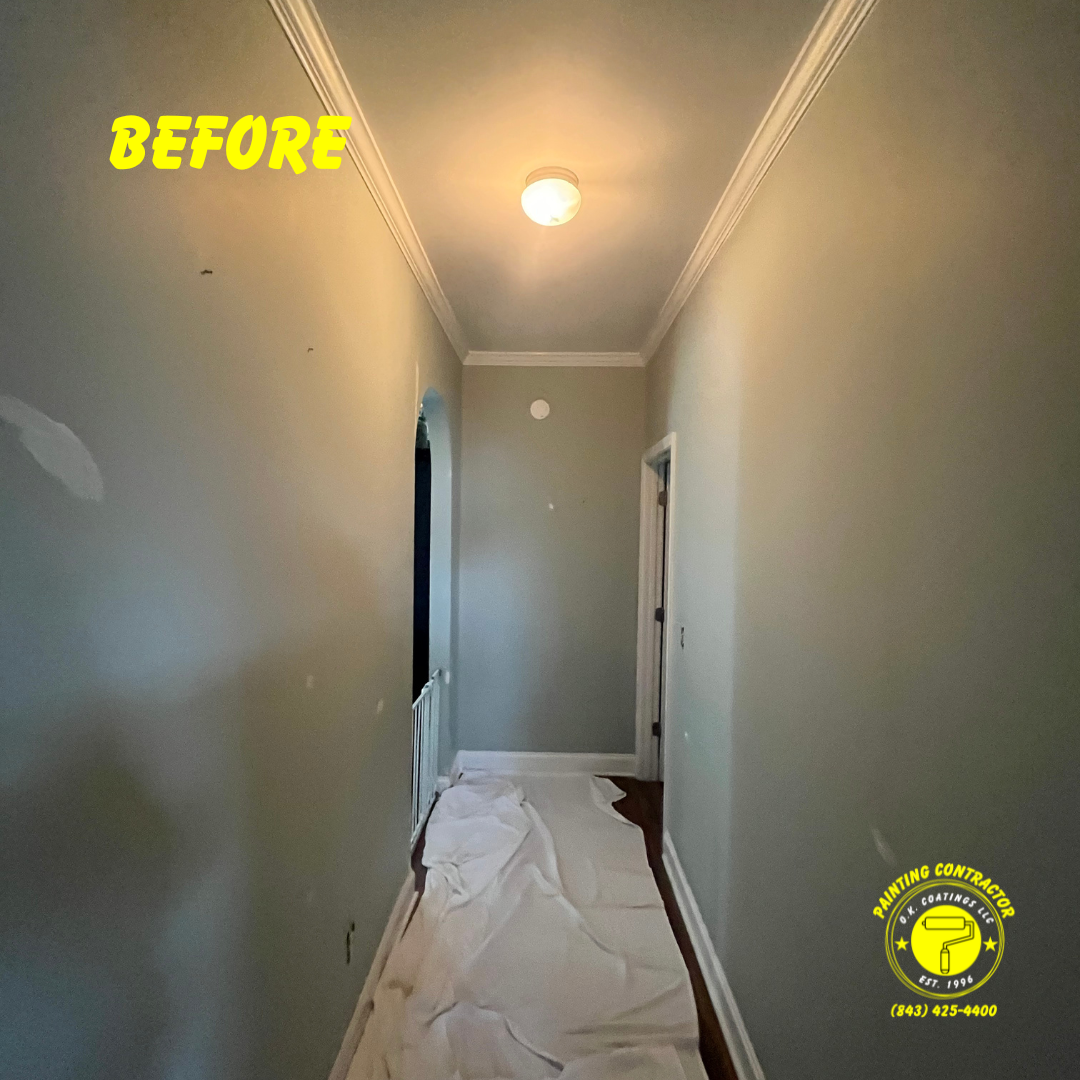 A hallway prepared for painting, featuring grey walls, crown molding, a central light, and a drop cloth on the floor.