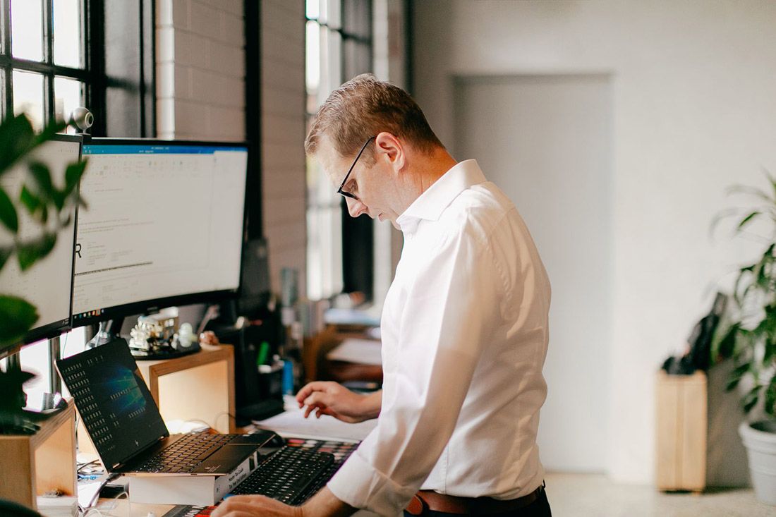 A Man is Standing at a Desk in Front of a Computer — Rochdale Accounting & Business Advisory in Alstonville, NSW