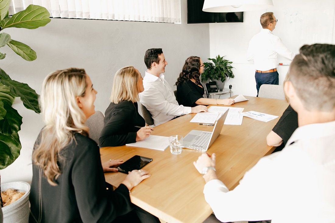 A Group of People Are Sitting Around a Table in a Room — Rochdale Accounting & Business Advisory in Alstonville, NSW