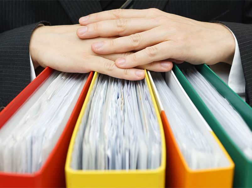 A Person is Holding a Bunch of Binders With Their Hands — Rochdale Accounting & Business Advisory in Alstonville, NSW