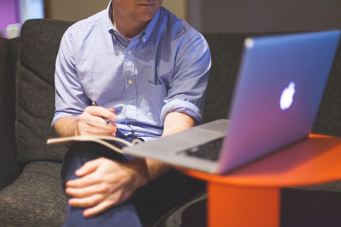 A Man is Sitting on a Couch With a Laptop and a Notebook — Rochdale Accounting & Business Advisory in Alstonville, NSW