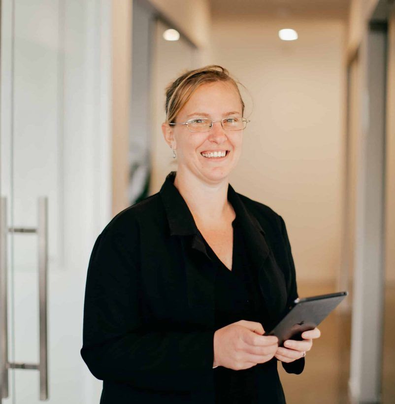 A Woman Wearing Glasses is Holding a Tablet and Smiling — Rochdale Accounting & Business Advisory in Casino, NSW