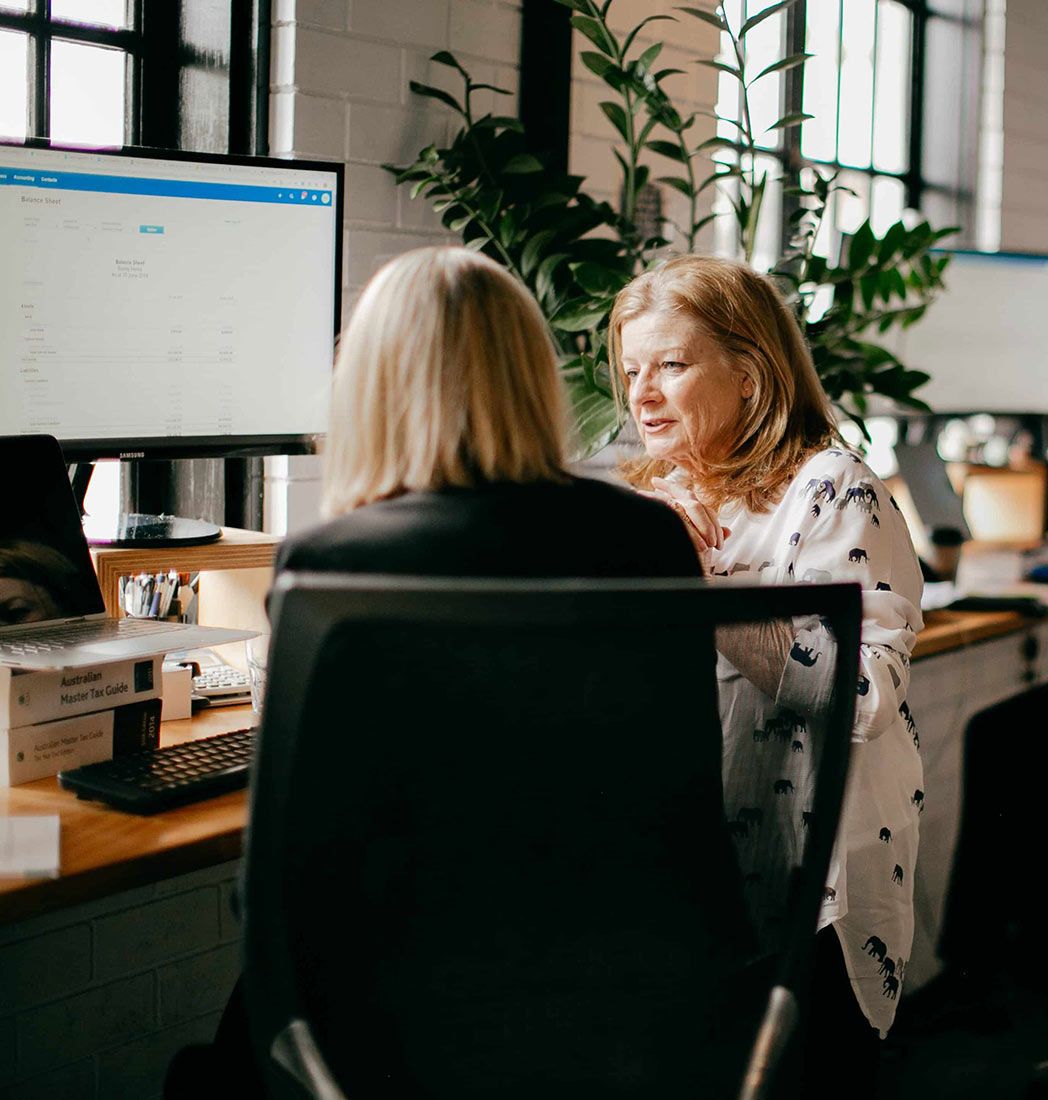 Two Women Are Sitting at a Desk in Front of a Computer — Rochdale Accounting & Business Advisory in Alstonville, NSW