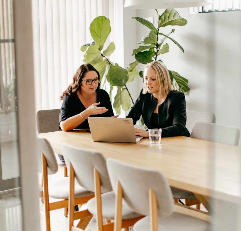 Two Women Are Sitting at a Table Looking at a Laptop — Rochdale Accounting & Business Advisory in Alstonville, NSW