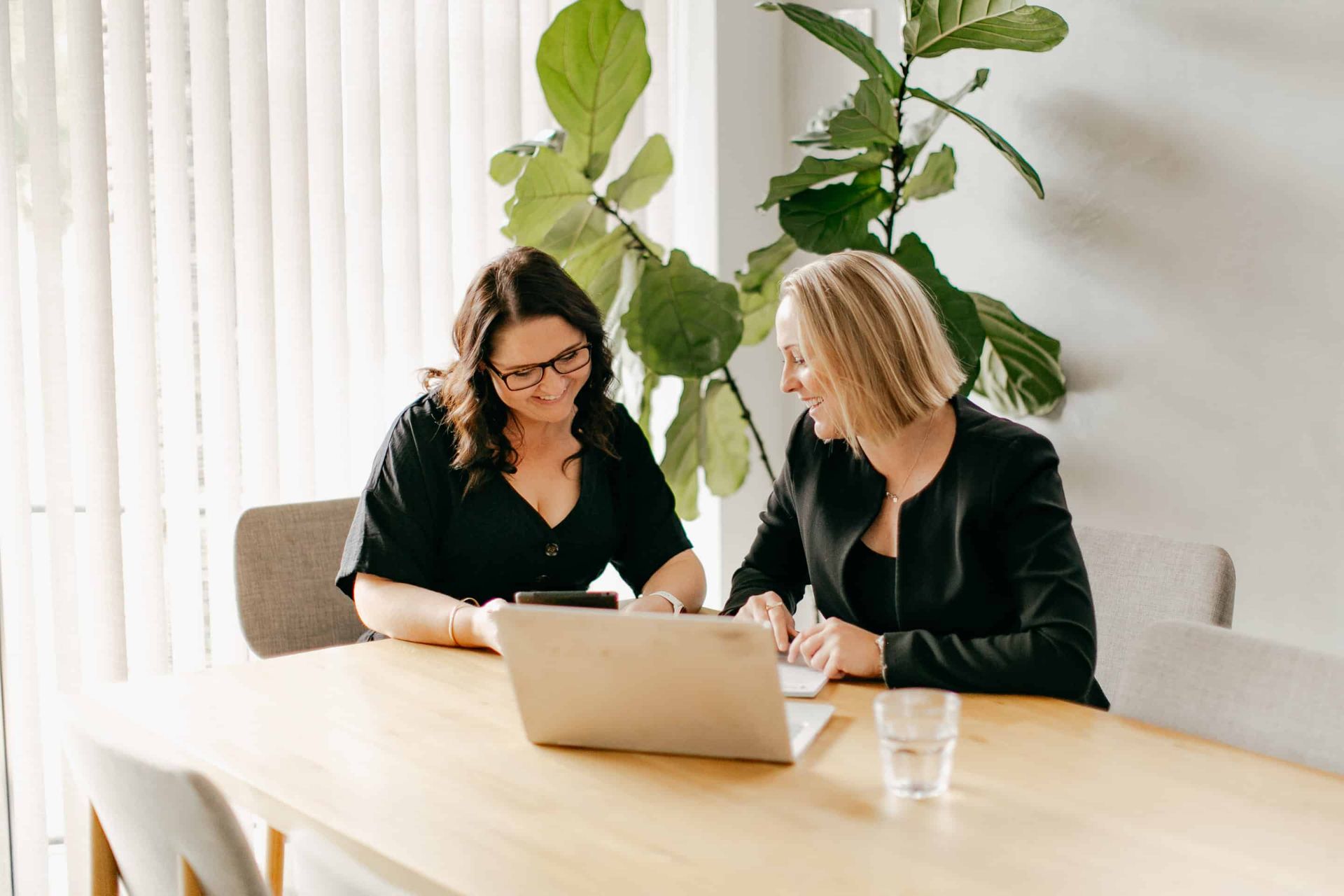 Two Women Are Sitting at a Table Looking at a Laptop — Rochdale Accounting & Business Advisory in Ballina, NSW