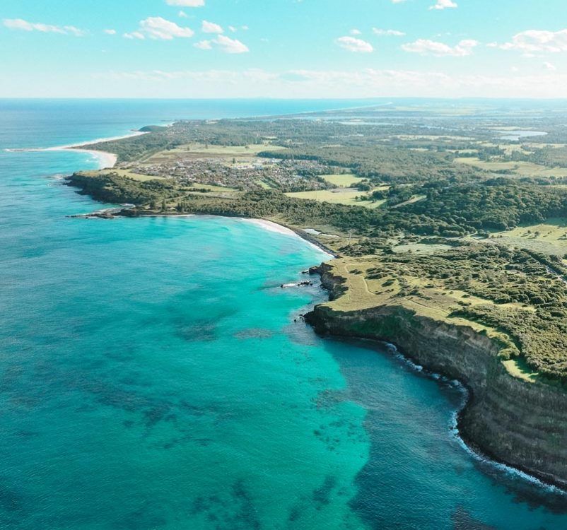 Turquoise ocean meets a green coastline, with cliffs, beach, and blue sky— Rochdale Accounting & Business Advisory in Alstonville, NSW