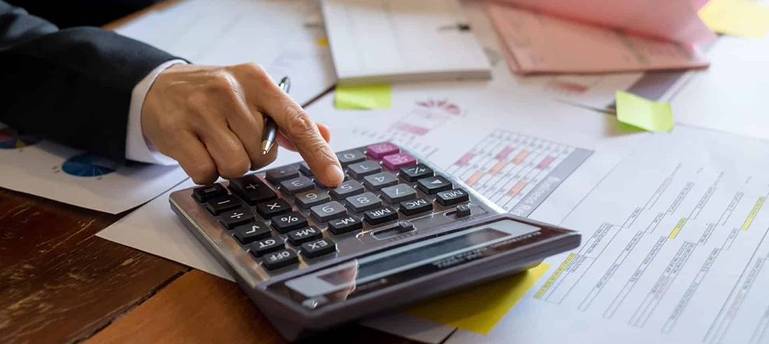 A Person is Using a Calculator on a Wooden Table — Rochdale Accounting & Business Advisory in Alstonville, NSW