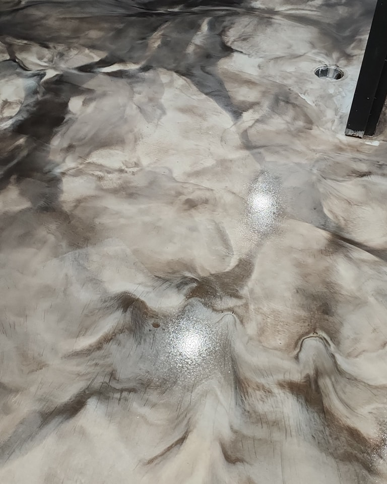 Swirled epoxy floor with white, gray, and brown tones, reflecting light.