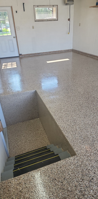 Interior view of a room with polished terrazzo flooring and a staircase leading down.