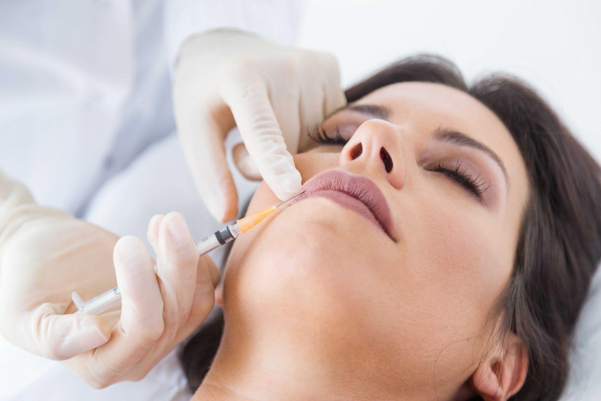 A woman is getting a botox injection in her lips.