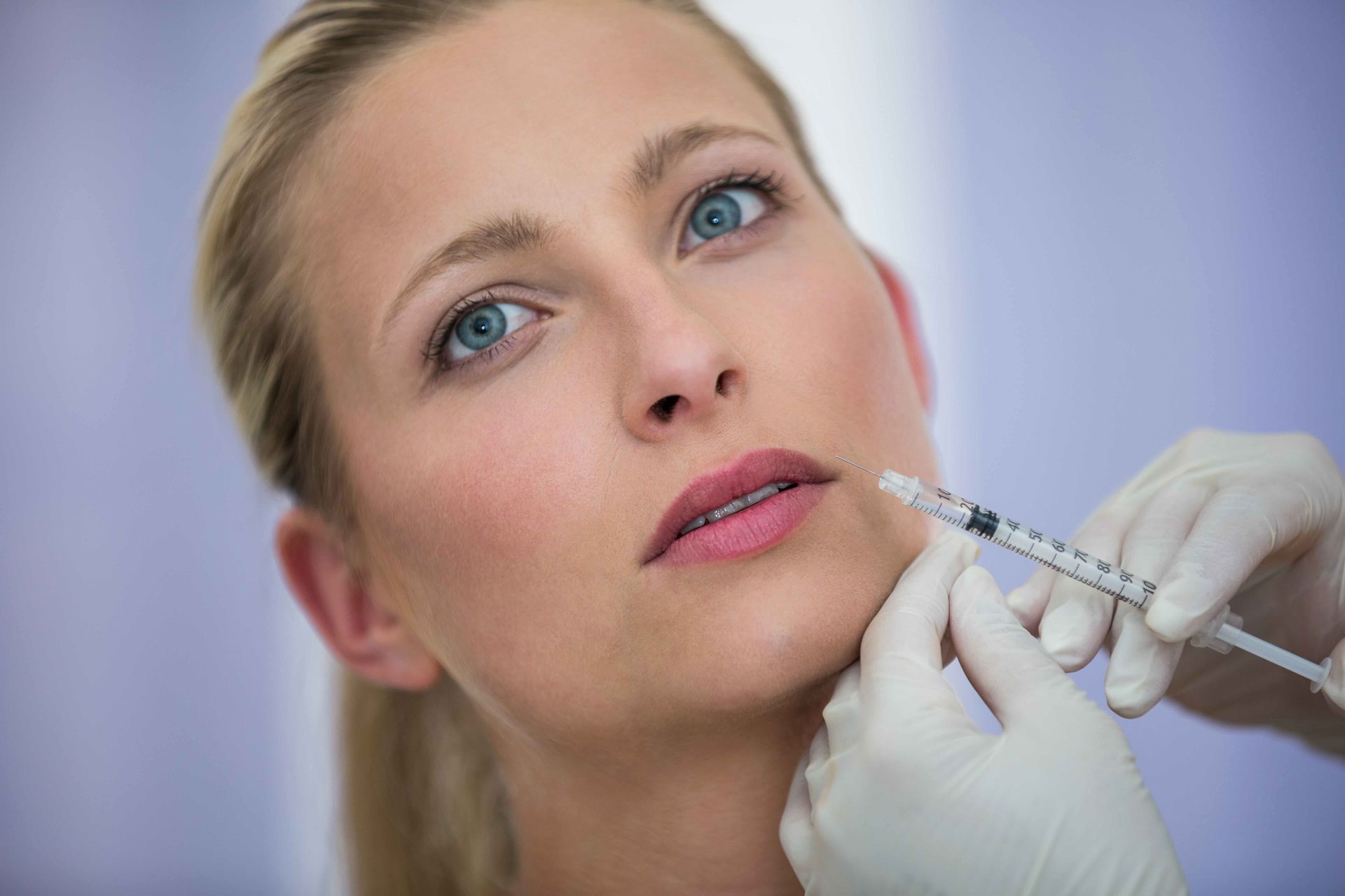 A woman is getting a botox injection in her lips.