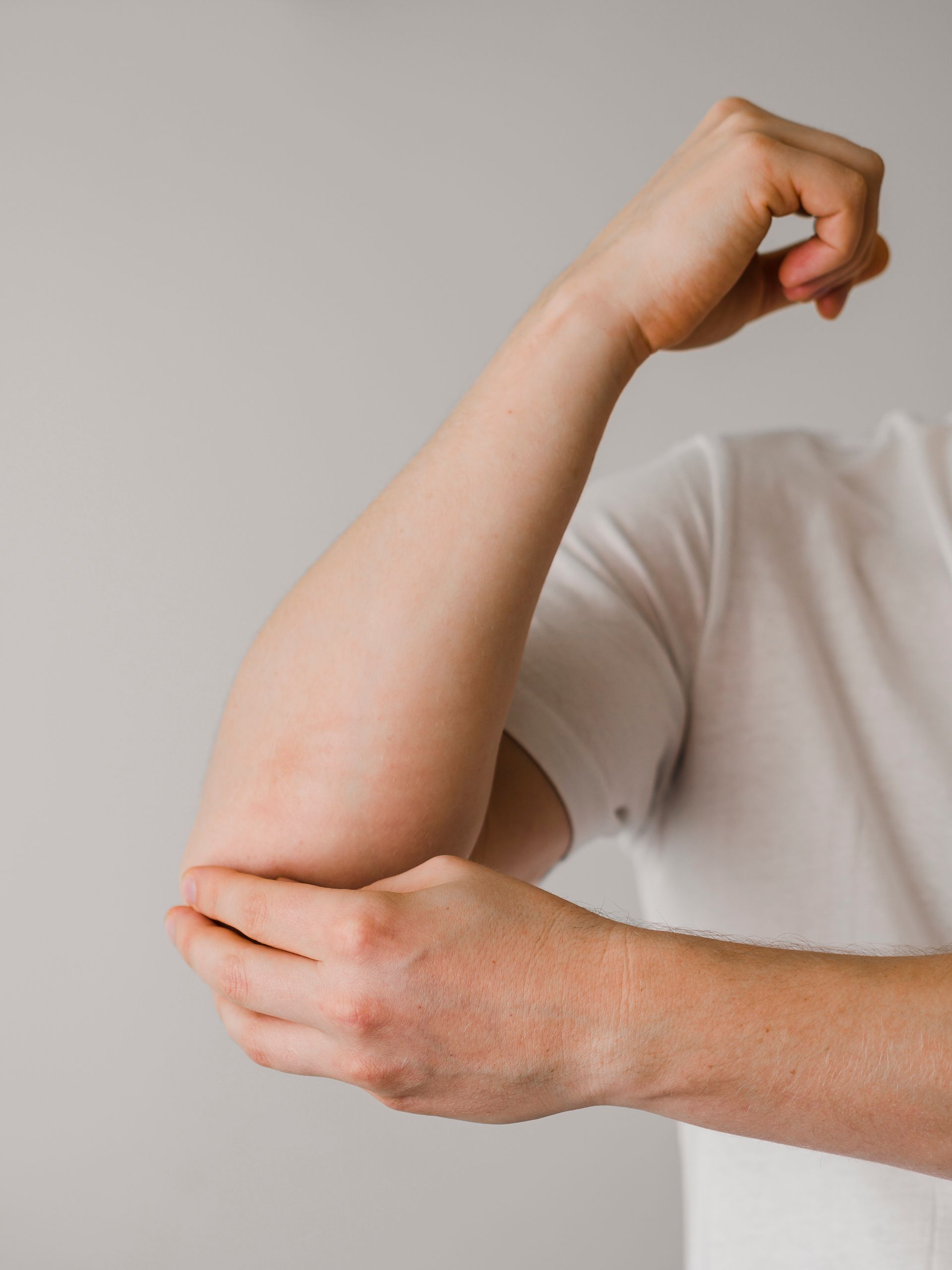 A man in a white shirt is flexing his arm