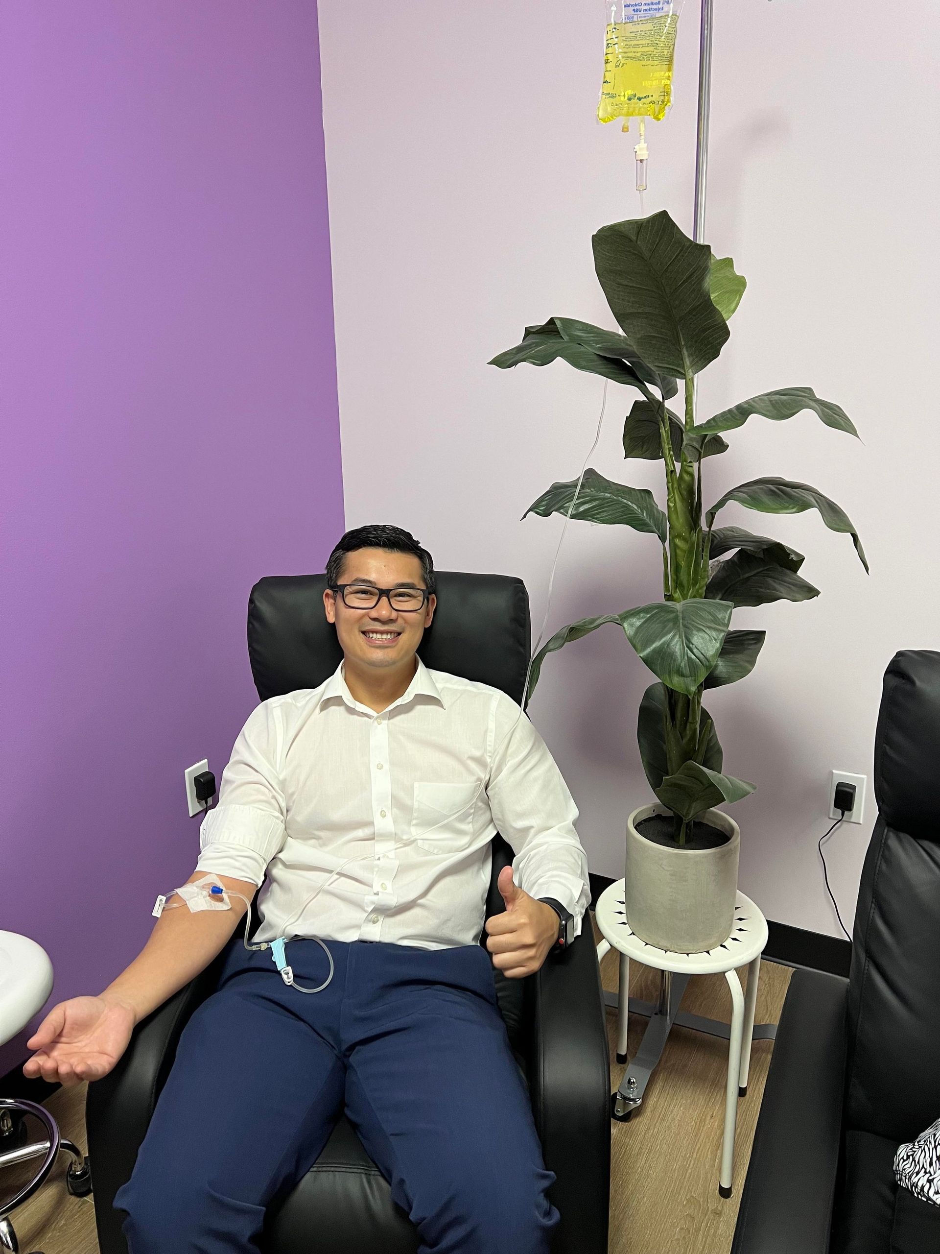 A man is sitting in a chair with an iv in his arm.