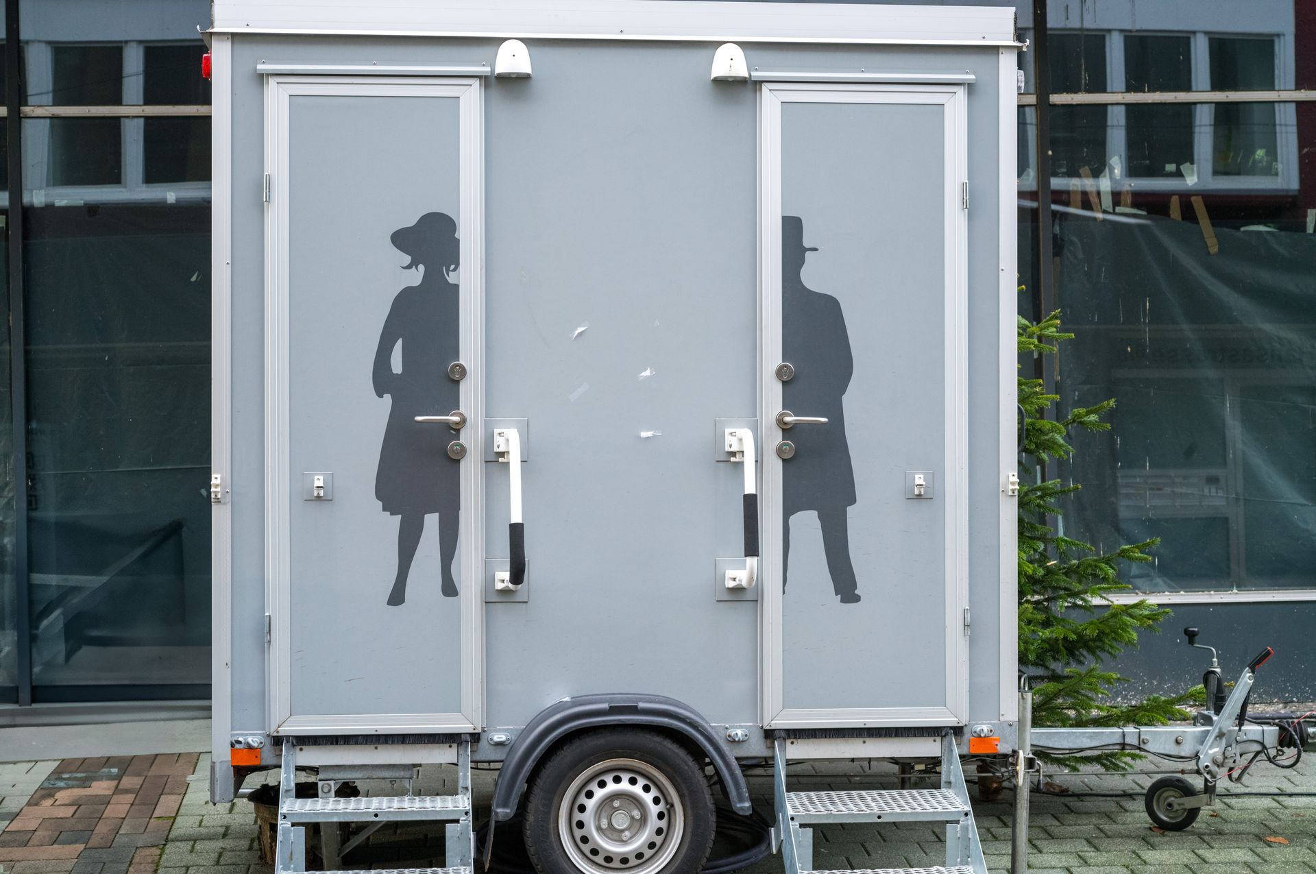 Mobile toilet trailer displaying gender symbols for men and women’s restrooms.