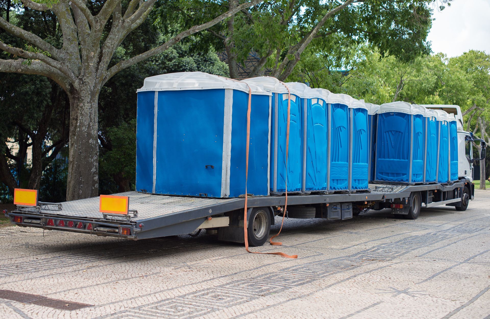 Portable restroom trailer loaded onto a truck for transport.