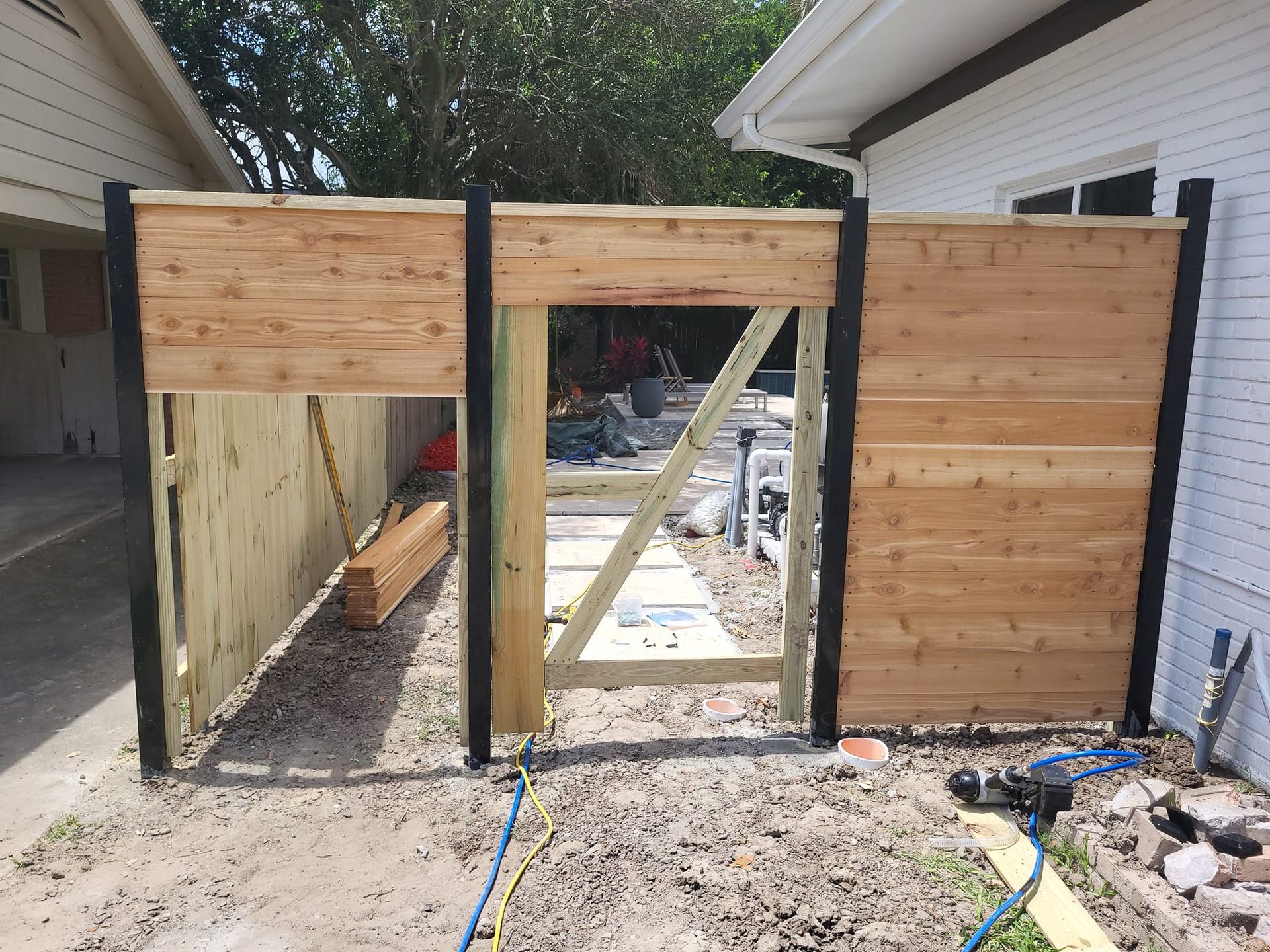 A wooden fence with a gate is being built in front of a house.
