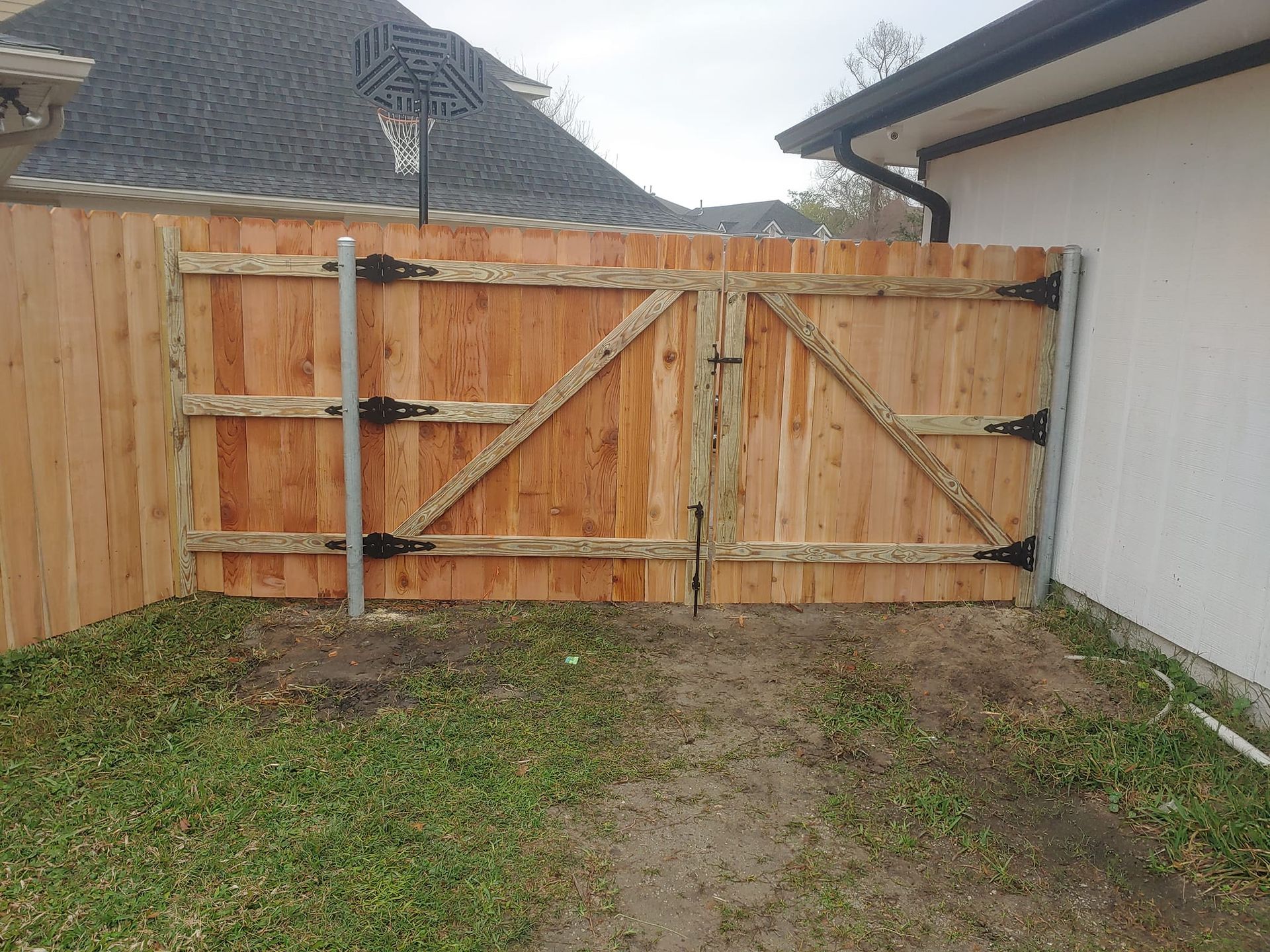 A wooden fence with a gate in the backyard of a house.
