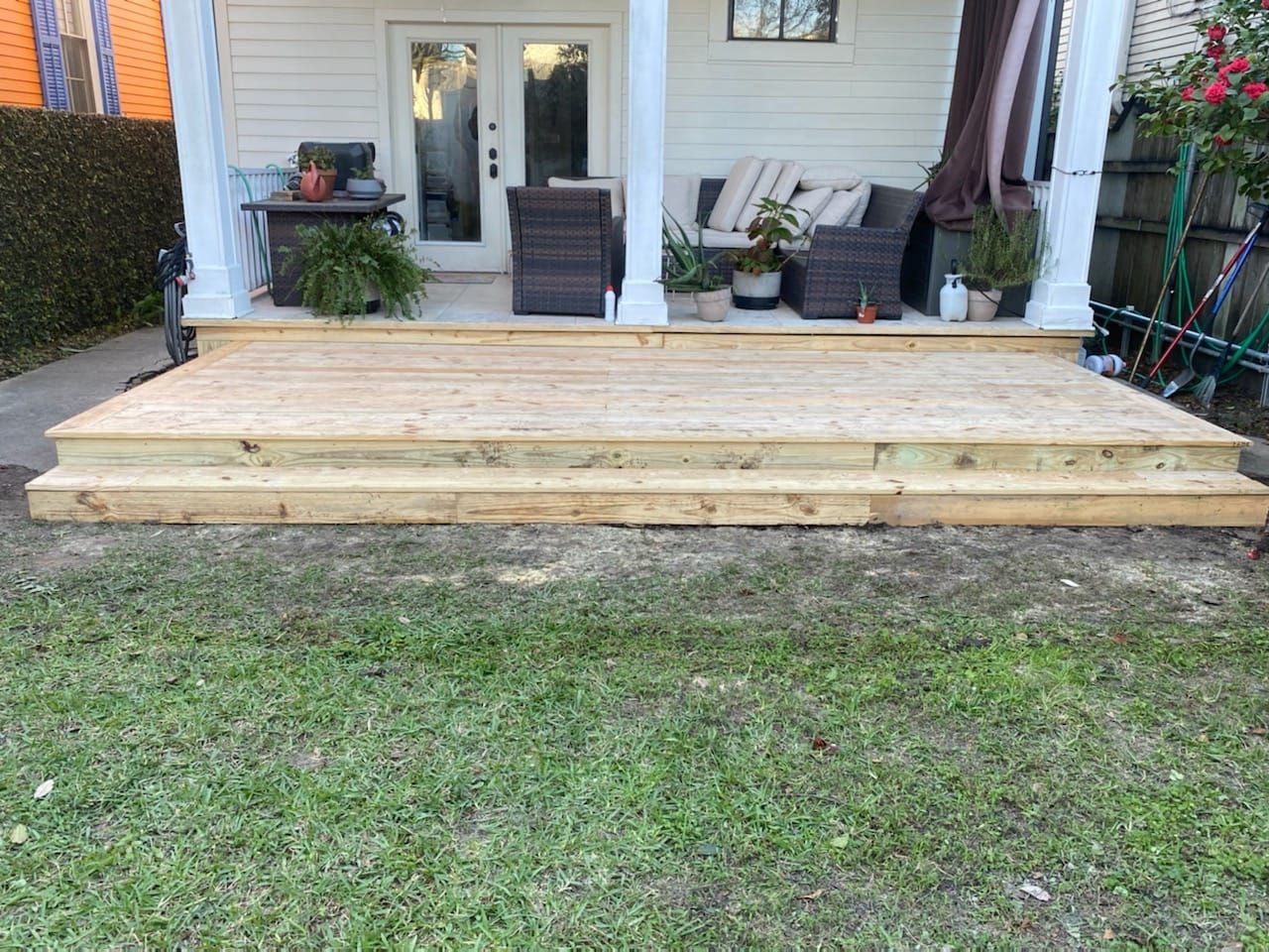 A wooden deck is sitting on top of a lush green lawn in front of a house.
